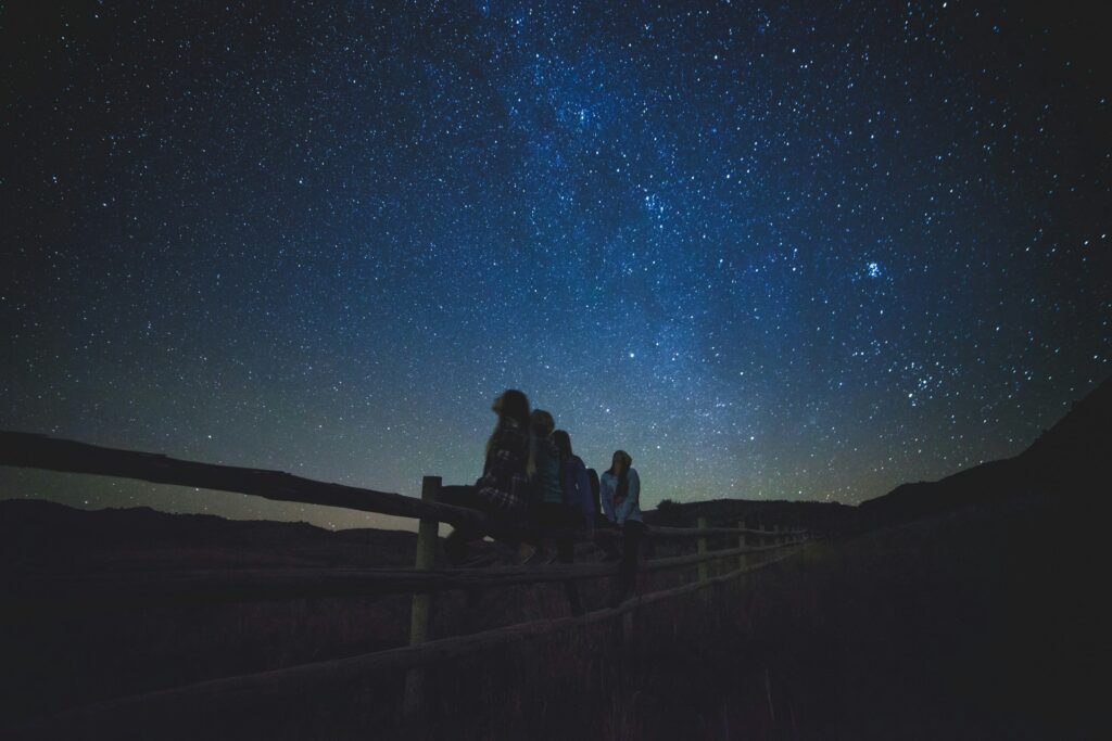 Women sitting on a fence under a starry sky